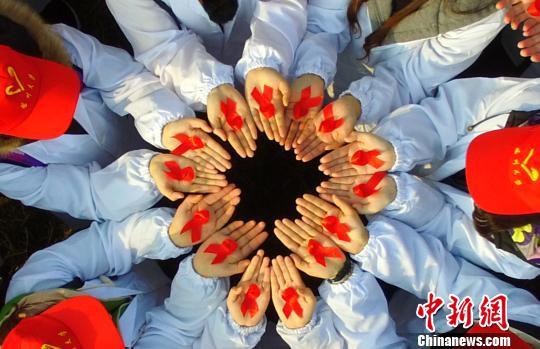 图为大学生展示防艾标志红丝带。 孟德龙 摄