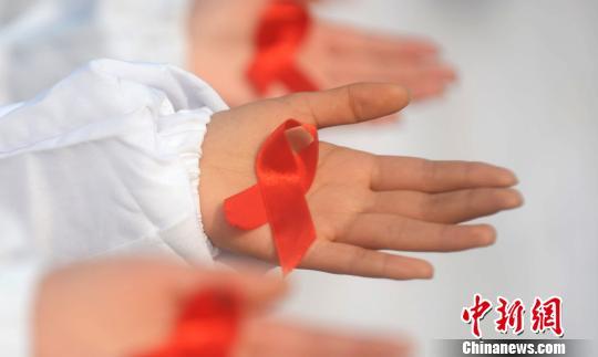 图为大学生展示防艾标志红丝带。 孟德龙 摄