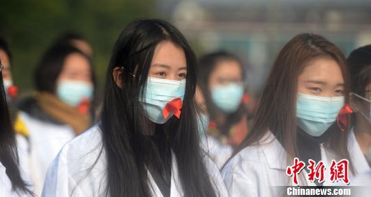 图为大学生们戴粘有红丝带的口罩。 孟德龙 摄